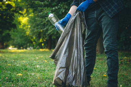 man-cleans-up-forest-throws-bottle-into-trash-bag-closeup_freepik